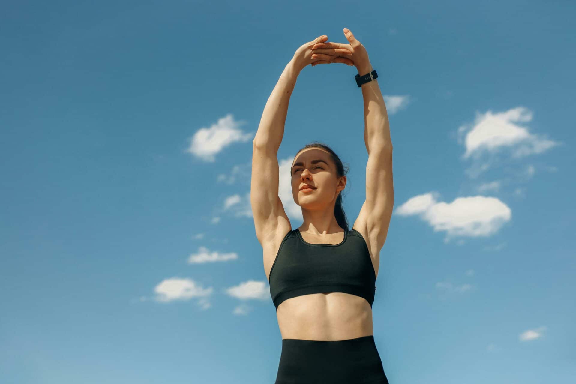 Mujer estirando los brazos hacia arriba antes de entrenar al aire libre