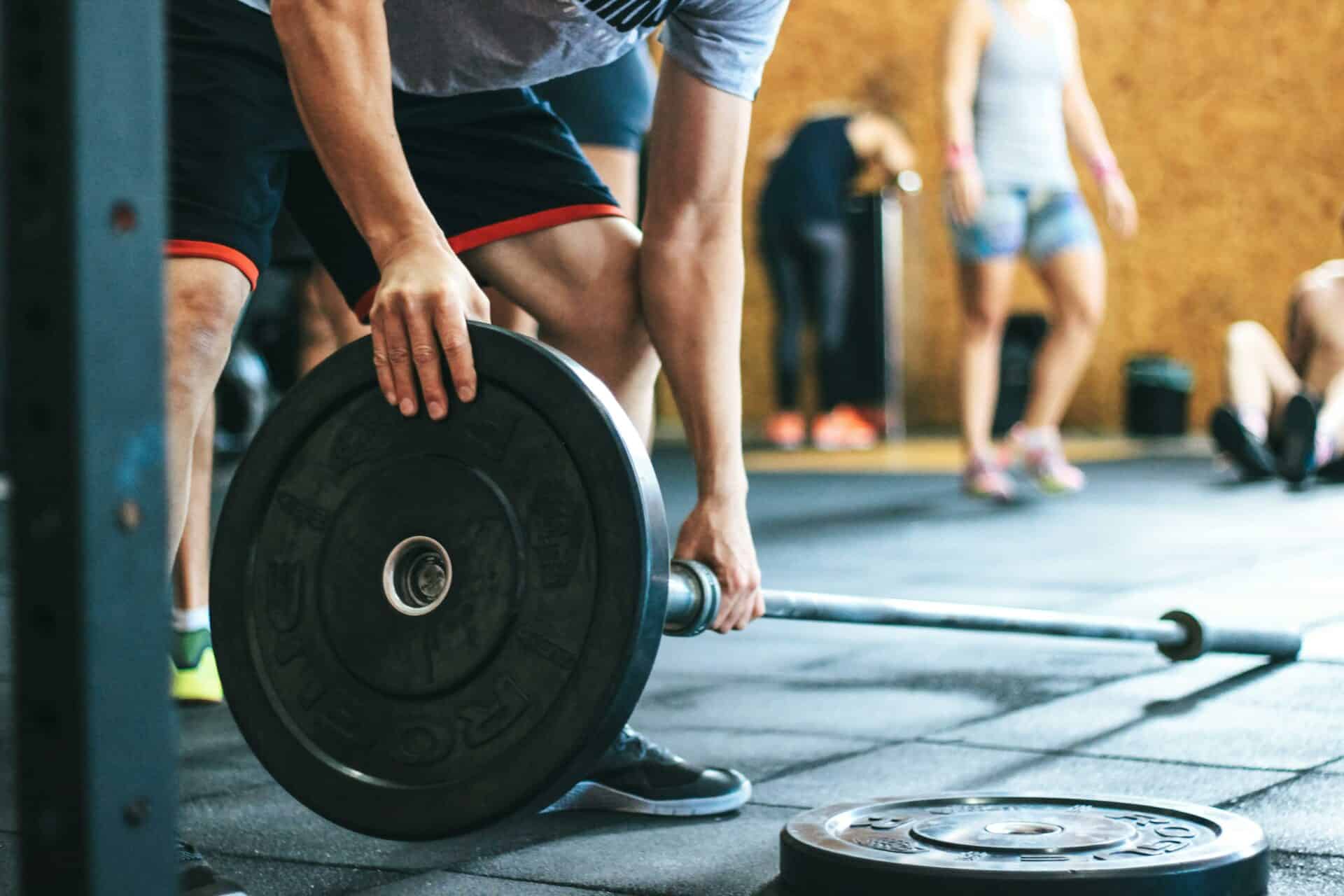 Persona colocando un disco en una barra durante un entrenamiento de fuerza